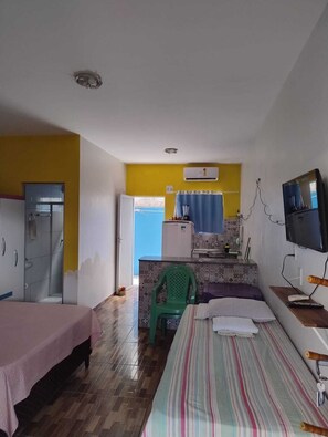 A compact room with two beds, a kitchenette, a bathroom, and a TV.