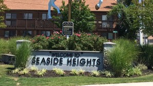 Eine weiße Pferdestatue mit bunten Verzierungen, eine amerikanische Flagge und ein Schild, das Besucher nach Seaside Heights willkommen heißt.