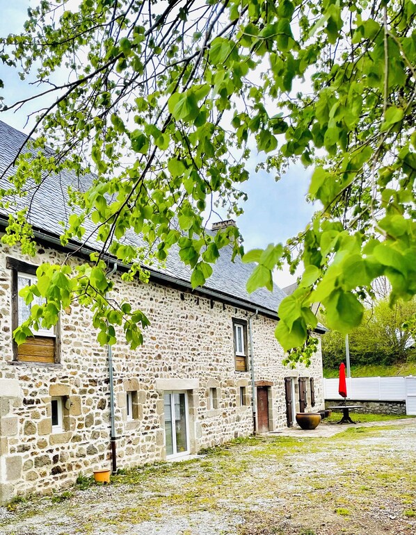 Un bâtiment en pierre doté d’un toit en pente, de nombreuses fenêtres et d’une porte.