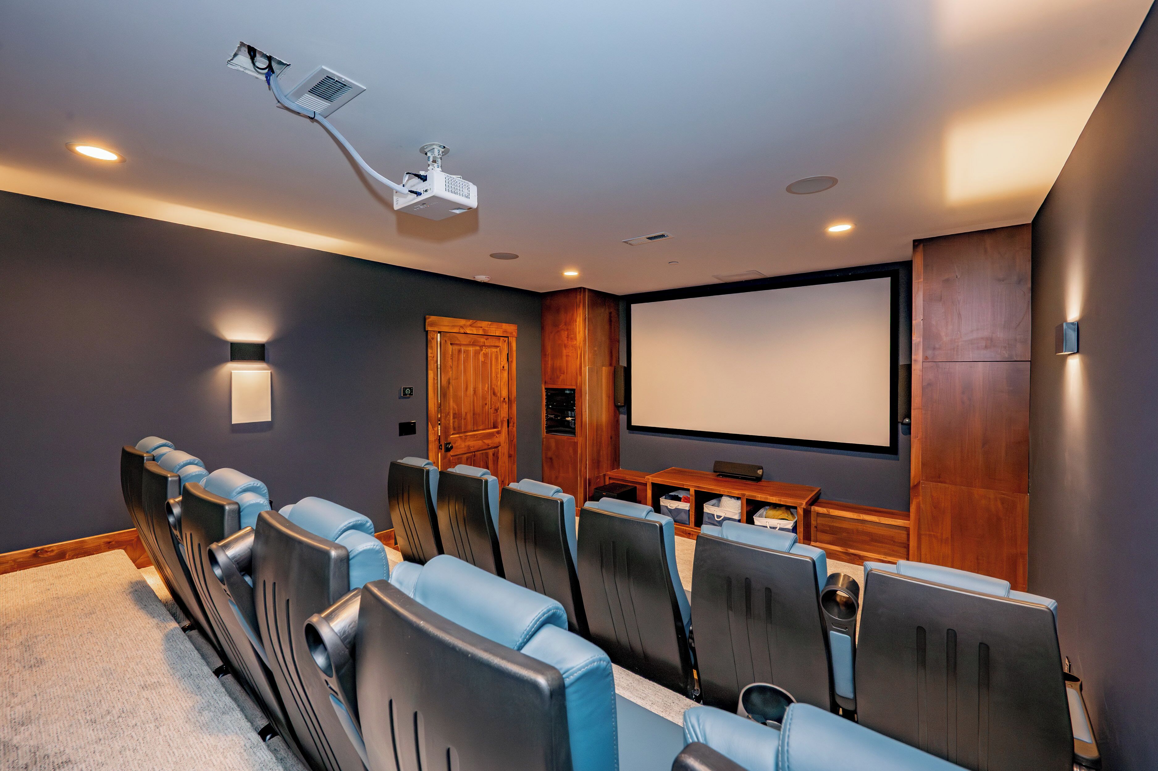 Une salle de cinéma privée avec des rangées de sièges, un grand écran et un projecteur.
