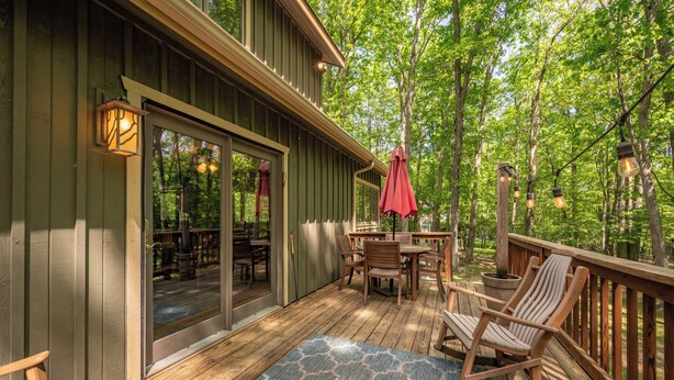 A wooden deck with a table and chairs, a rocking chair, and a red umbrella. - New! Cute Hideaway w/ Hot Tub & Amenities (Oakland)