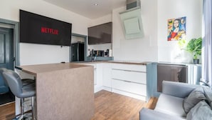 A modern kitchen with a built-in island, white cabinetry, and a black refrigerator. - Sheffield 4 Bed Home by Broomhill Village (Sheffield)