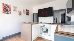 A modern kitchen with a built-in oven, a sink, and a flat-screen TV mounted above the stove. - Sheffield 4 Bed Home by Broomhill Village (Sheffield)