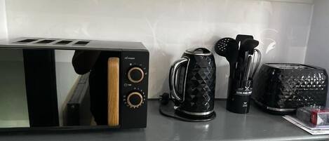 A kitchen counter with a toaster, a coffee maker, and a kettle.