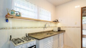 A compact kitchen with a gas stove, a microwave, and a sink. - House w/ Barbecue 140m From the Beach Shd0071 (Florianópolis)