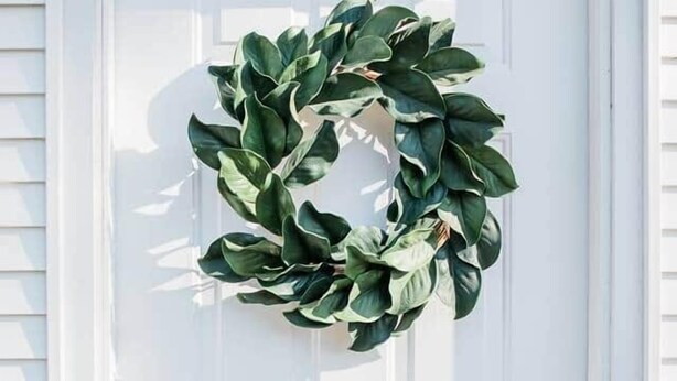 Een witte deur met een groene krans.