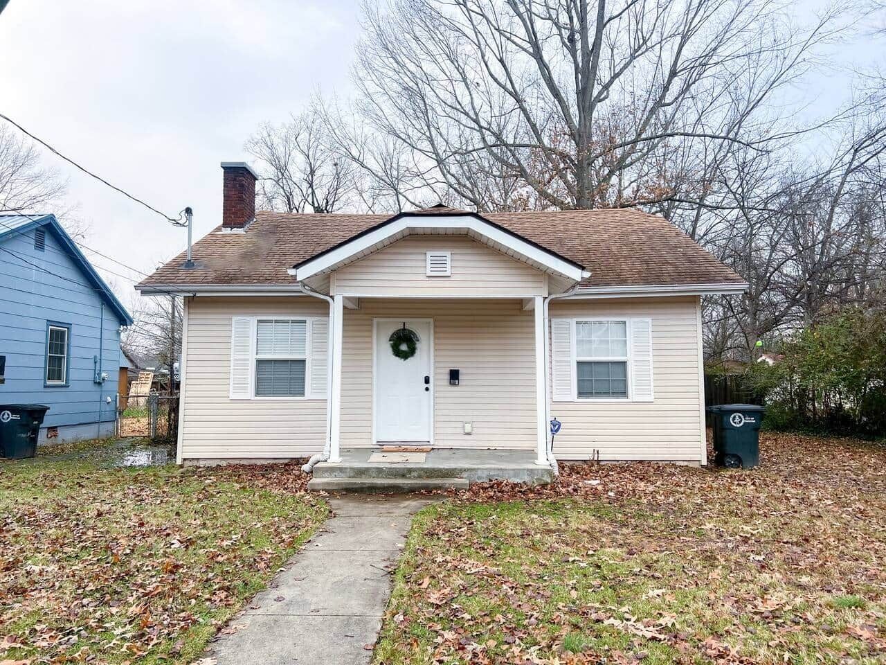 A single-story house with a front porch, a front door, and a small front yard.