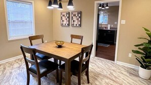 Un coin repas avec une table et des chaises en bois, un lustre et des œuvres d’art accrochées au mur.