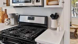 A compact kitchen with a built-in microwave, stove, and white cabinetry.