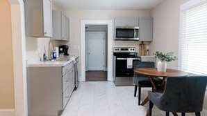 Cozinha compacta com área de refeições, com micro-ondas, forno e pia.