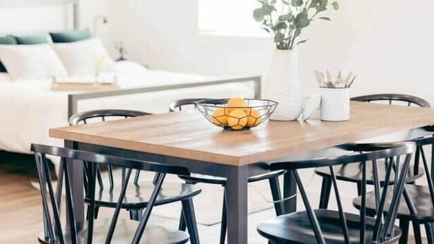 A dining area with a round wooden table, black chairs, and a modern chandelier. - Commonwealth Cottage (McCracken County)