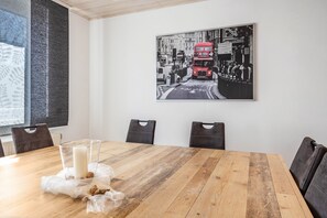 Ett konferensrum med ett träbord, stolar, ett glas mjölk och ett svartvitt fotografi av en röd dubbeldäckarbuss på väggen.