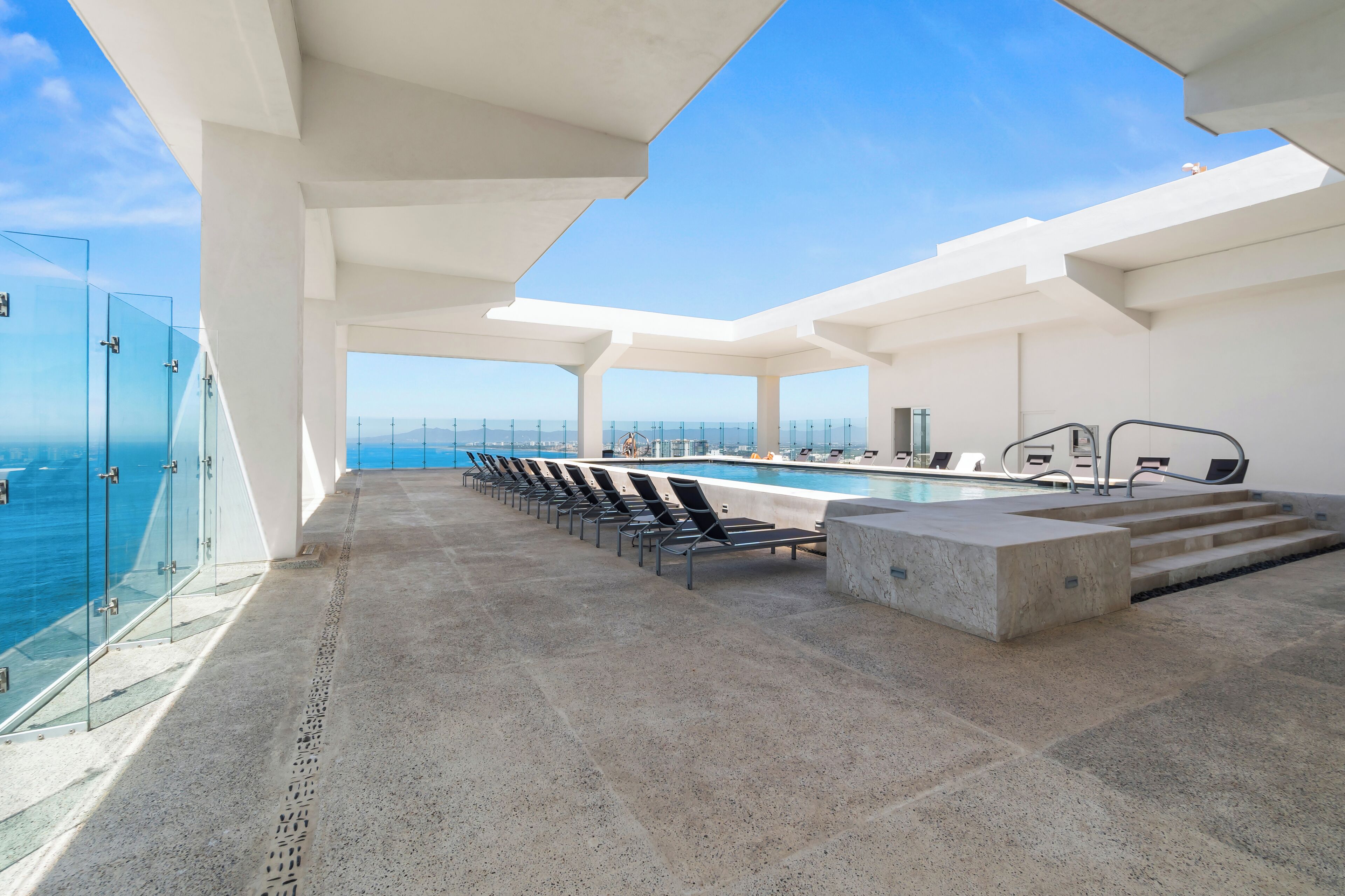 A rooftop pool area with clear views of the ocean and a modern architectural design.