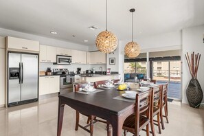 Una cucina moderna con zona pranzo, elettrodomestici in acciaio inossidabile e un'ampia finestra.