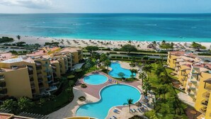 Un complexe hôtelier doté de plusieurs piscines, situé en bord de mer et comprenant différents bâtiments.