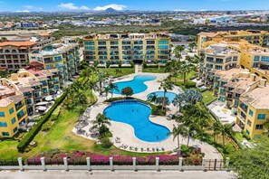 Un resort con diversi edifici, una piscina centrale e vegetazione circostante.