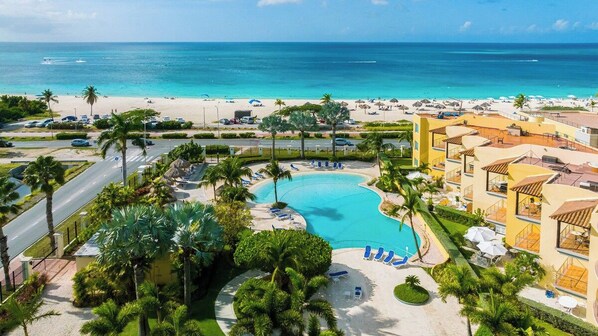A resort with a swimming pool, beach, and ocean view.