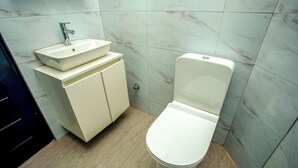 A bathroom with a white sink, toilet, and cabinet. - Tranquil 4-bedroom apartment with AC in Dawhenya (Dawhenya)