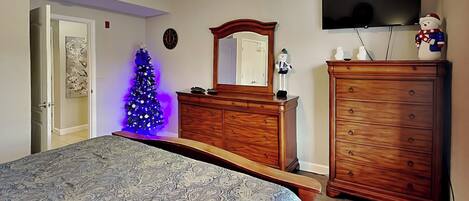 A bedroom with a bed, dresser, and a television on the wall.