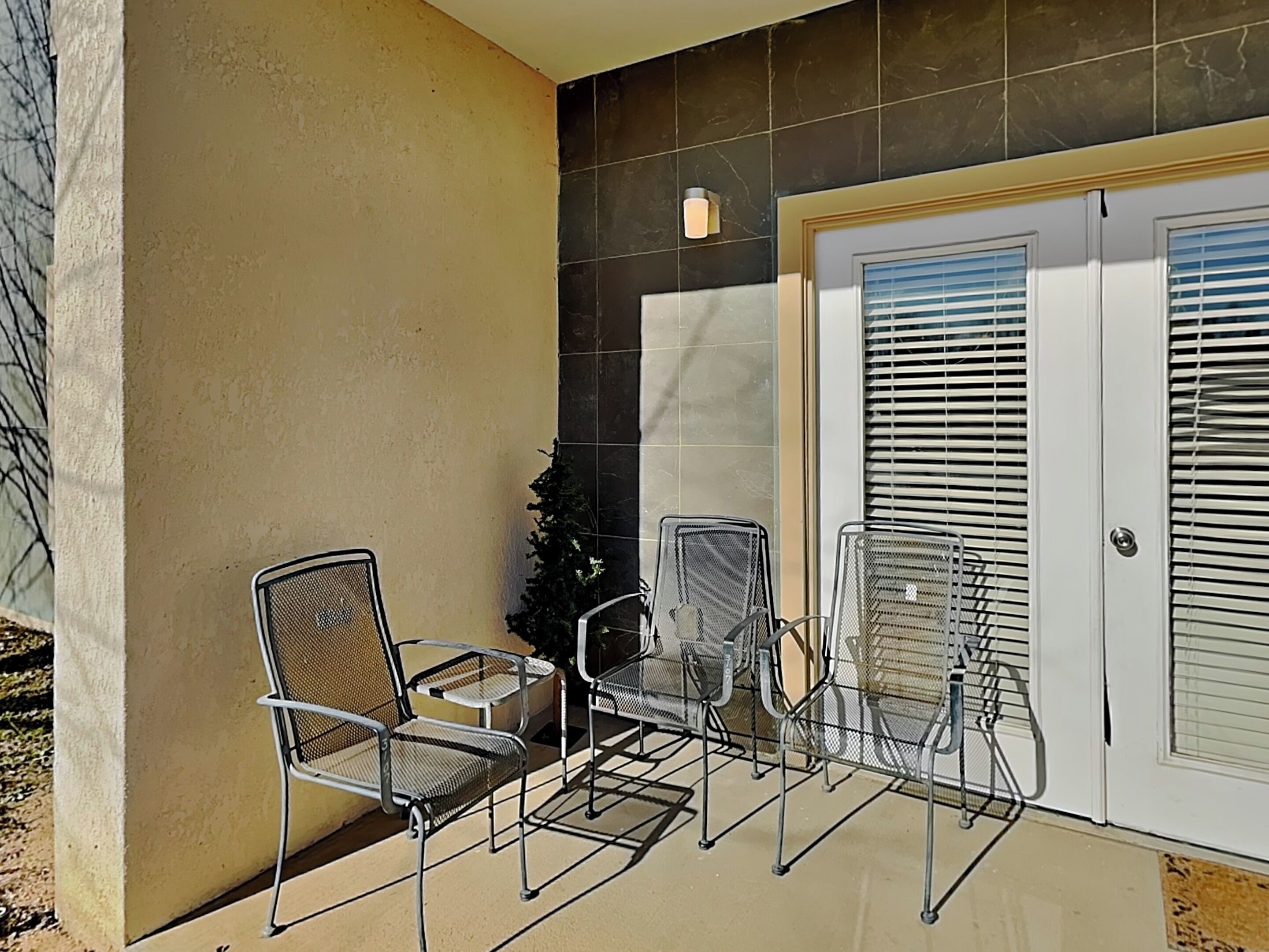 Un espace patio avec des chaises en métal et une petite plante.