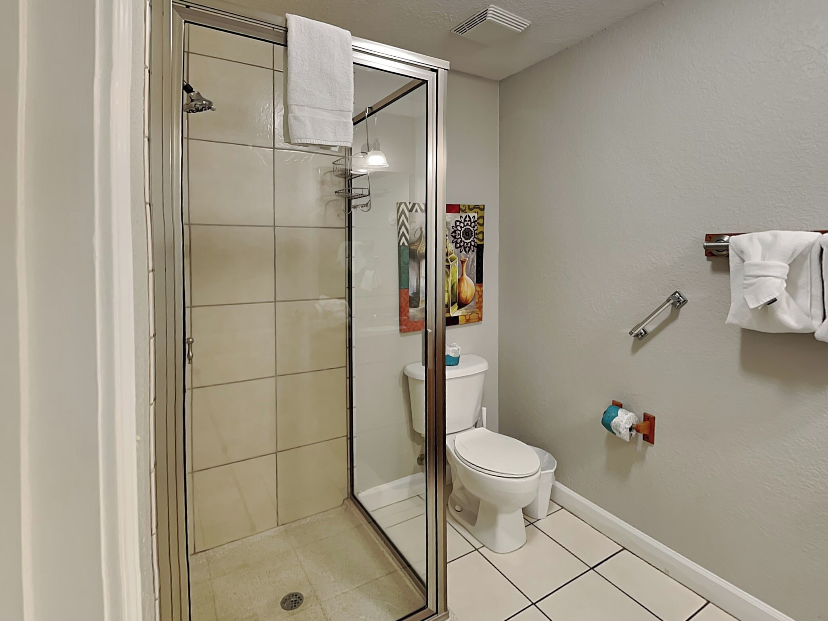 A bathroom with a glass-enclosed shower, a toilet, and a sink.