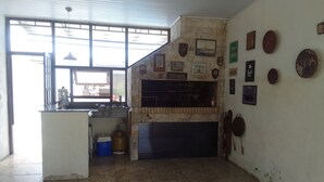Eine Küche mit Gasherd, Spüle und Fliesenboden. Mehrere gerahmte Bilder sind an der Wand angebracht.