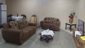 Ein Wohnzimmer mit zwei Sofas, einem kleinen Tisch und einem Essbereich mit Tisch und Stühlen.