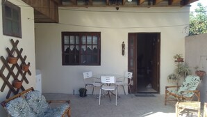Eine Terrasse mit Tisch und Stühlen, eine hölzerne Bank und Kübelpflanzen.