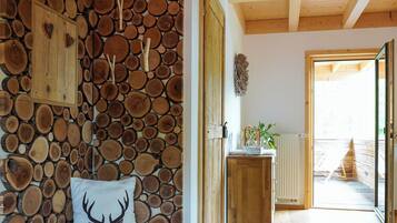 Ein Zimmer mit einer Holzwand aus Baumstämmen, einer Bank mit einem Deer-förmigen Kissen und einem Holztisch mit einer Pflanze.