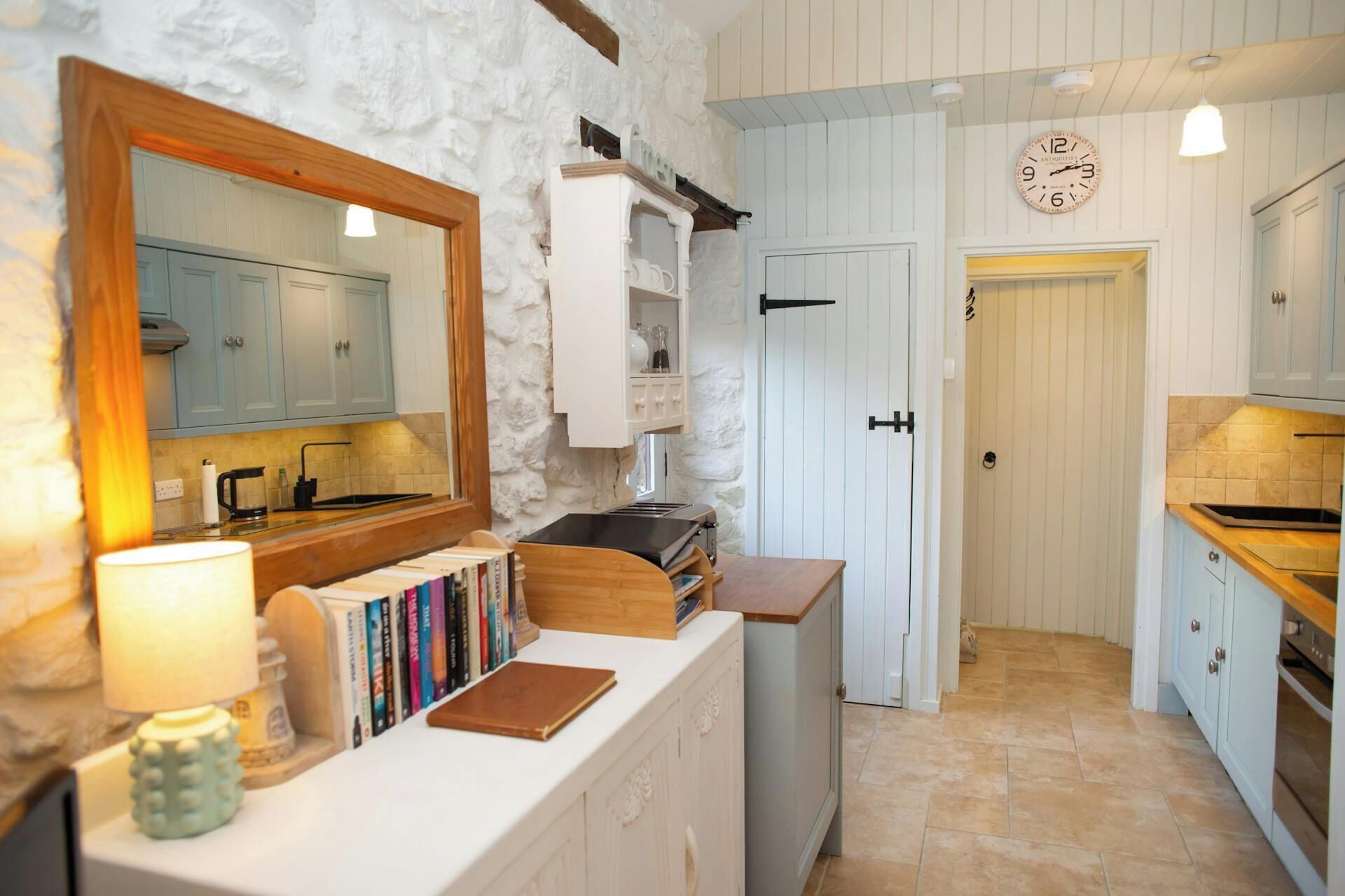 A kitchen with white cabinets, a wooden countertop, a stove, and a bookshelf with books.