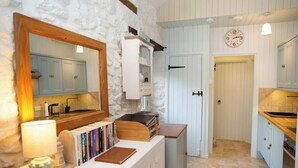 A kitchen with white cabinets, a wooden countertop, a stove, and a bookshelf with books. - Little Rogeston Cottage, Nolton Haven (Nolton Haven)
