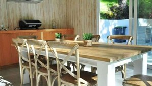 Une cuisine moderne avec une table et des chaises en bois, un four encastré et une vue sur la verdure.