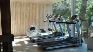 Une salle de sport équipée de tapis de course et d’un appareil elliptique, dotée de grandes fenêtres et d’un mur en bois.