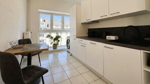 A modern kitchen with white cabinets, a black countertop, and a window with a view of buildings. - Central apartment in Düsseldorf: 2 beds, elevator, WiFi – Ideal for trade fairs (Düsseldorf)