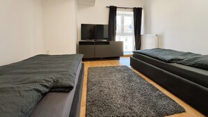 A room with two beds, a TV, and a window with curtains. - Central apartment in Düsseldorf: 2 beds, elevator, WiFi – Ideal for trade fairs (Düsseldorf)