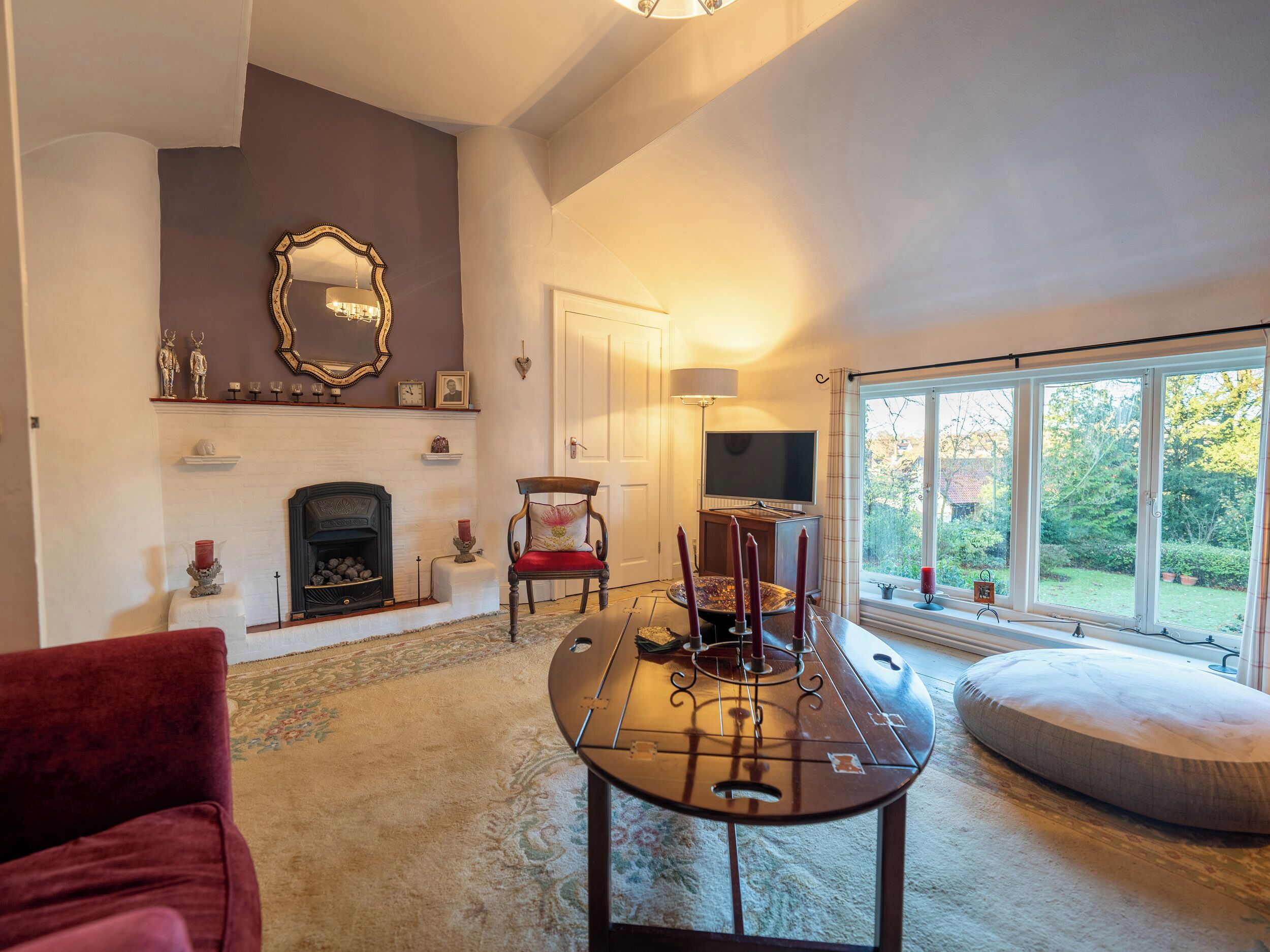 A living room with a fireplace, a television, and a large window with a view of the outdoors.