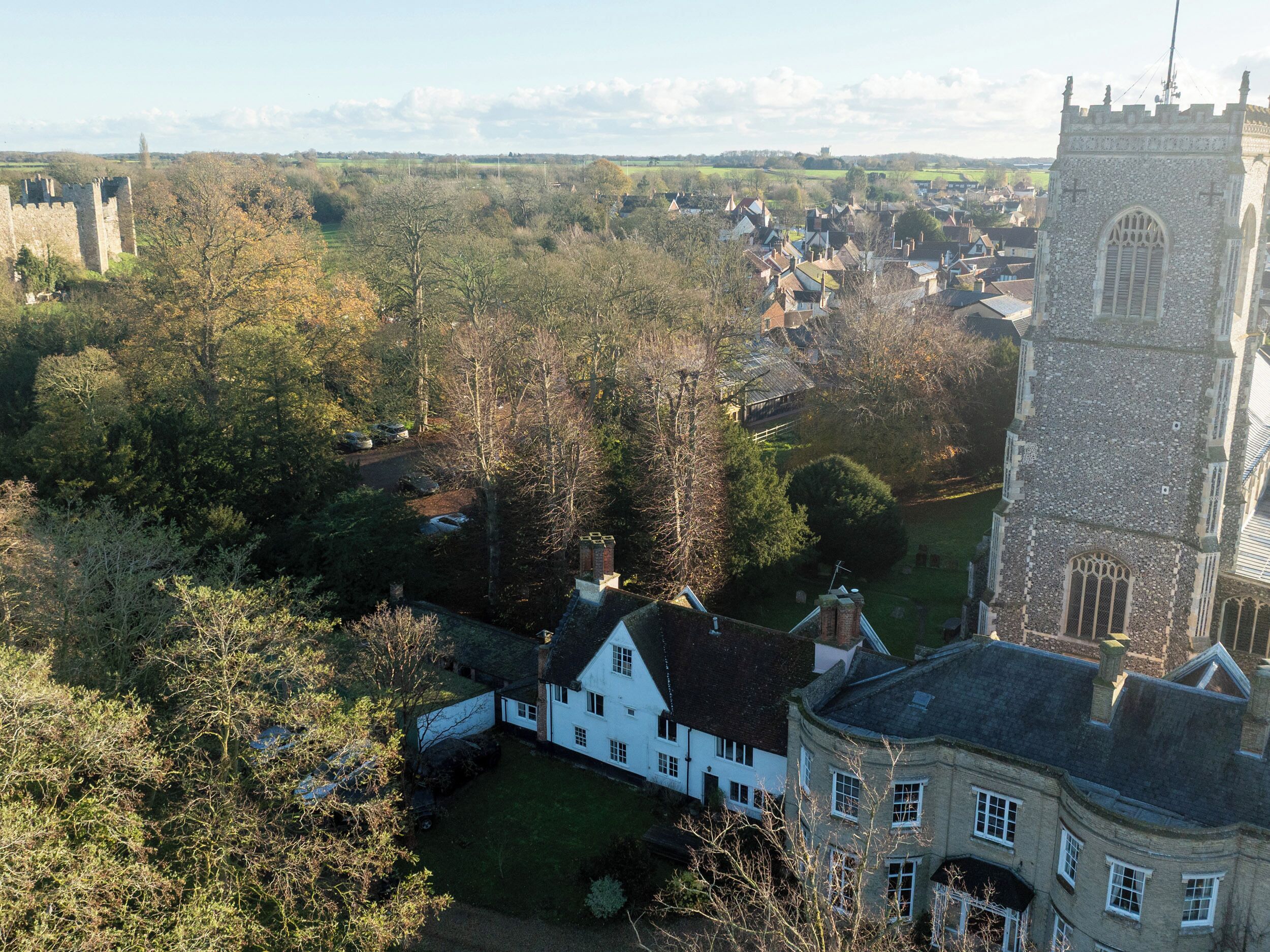 A historic town with a prominent church tower, surrounded by traditional buildings and lush greenery.