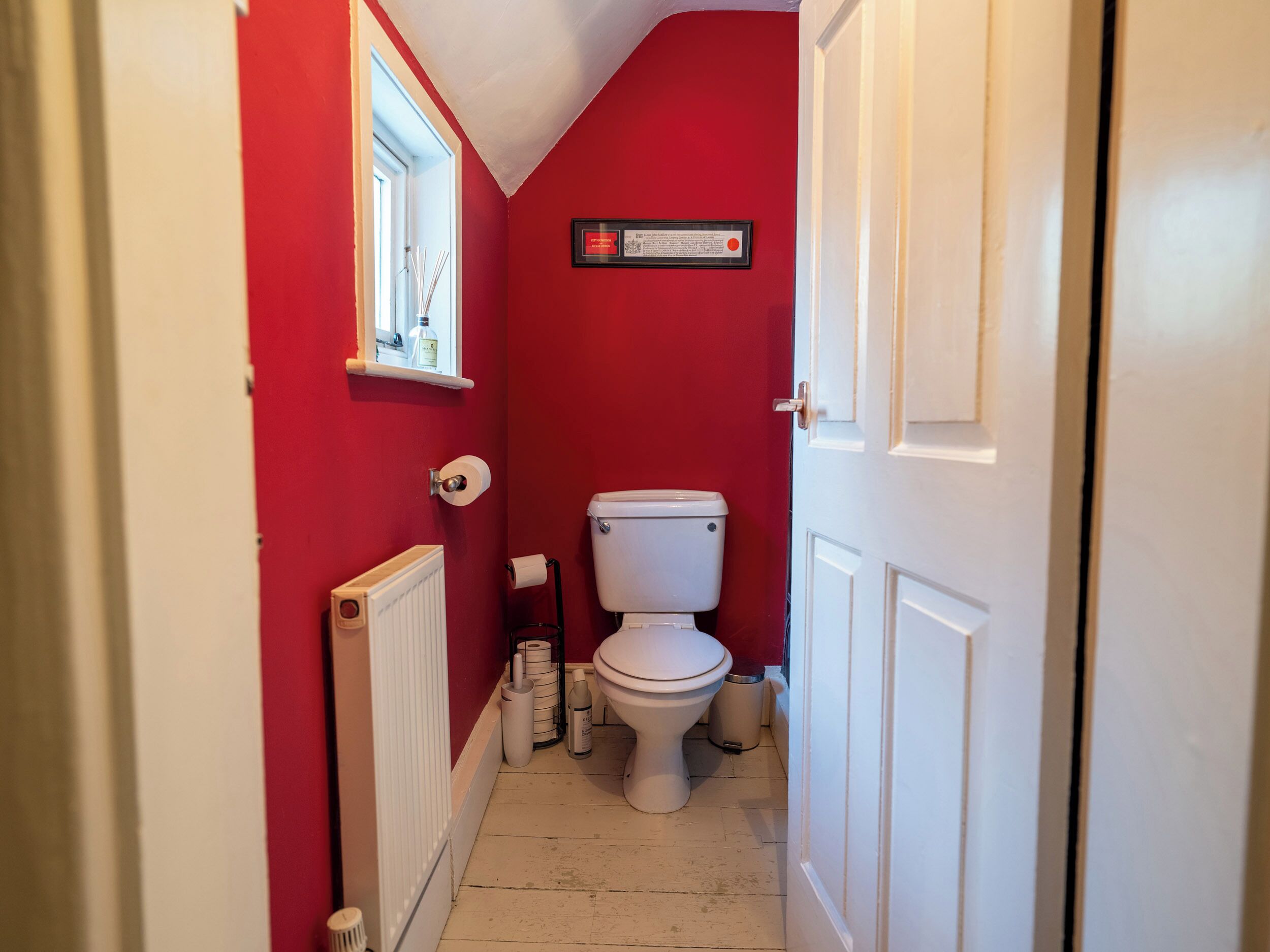A narrow hallway with a red wall, a white door, and a white radiator.