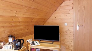 Puupaneloitu huone, jossa on pöydällä televisio, vedenkeitin ja kahvinkeitin.