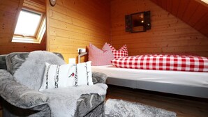 Una habitación acogedora con una cama, una silla, un ventanal y un reloj en la pared.
