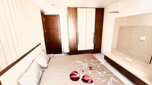 Une chambre à coucher comprenant un lit, une armoire en bois et une tête de lit ornée d’un panneau texturé.