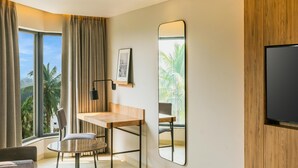 A modern room with a large window, a wooden desk, a chair, a round table, and a large mirror. - Park Inn & Suites By Radisson, Puri (Puri)