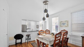 Un espace repas avec une table en bois, des chaises et des lampes suspendues.