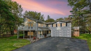 A two-story house with a front porch, a garage, and a stone foundation. - Huge home w/Game Room, Grill, Hot Tub, 3 living room, 2 bonus room, top location (Albrightsville)