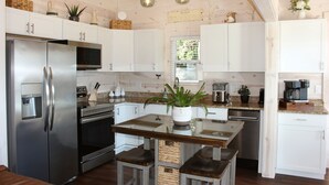 A modern kitchen with stainless steel appliances, white cabinets, and a central island with stools.