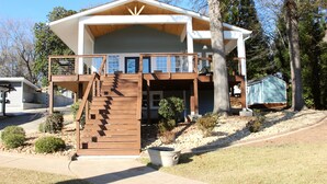 A two-story house with a wooden deck, a covered front porch, and a small garden area.