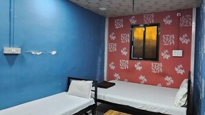 Una habitación con dos camas individuales, una mesa de madera, un ventilador de techo y paredes con diseño.