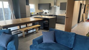 Eine moderne Küche mit einer zentralen Kochinsel, eingebauten Geräten und einem Essbereich mit einem Holztisch und Bänken.