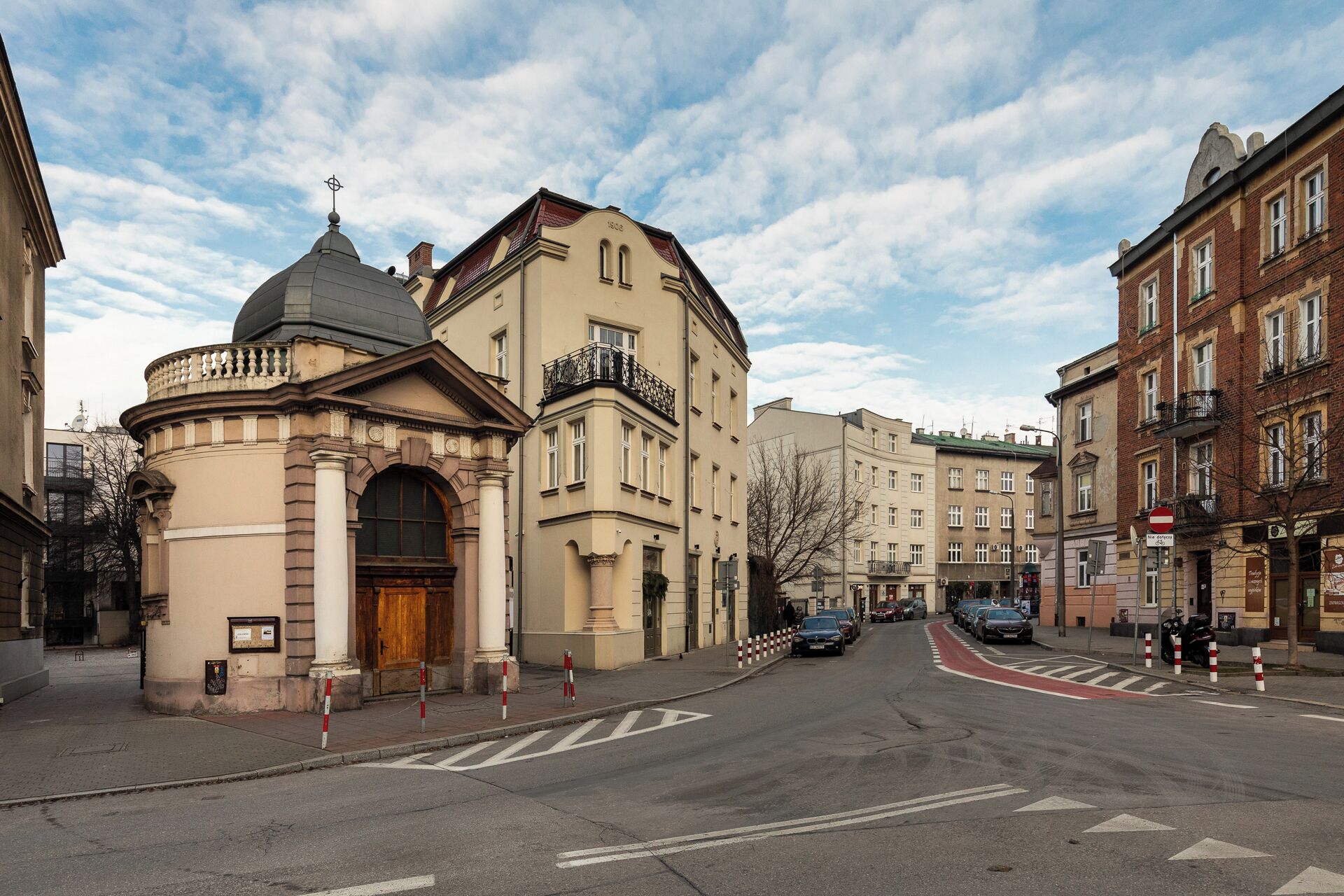A street with a historic building featuring a dome and arched entrance.