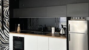 Une cuisine moderne dotée d’un four encastré, d’un réfrigérateur en acier inoxydable et d’un plan de travail noir.